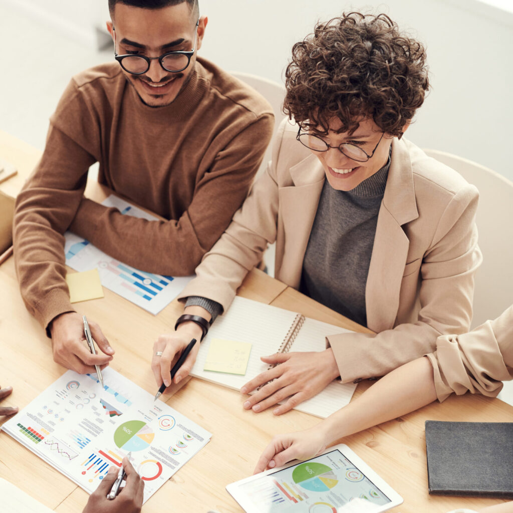 Group of people in a meeting happily reviewing graphs and business plans