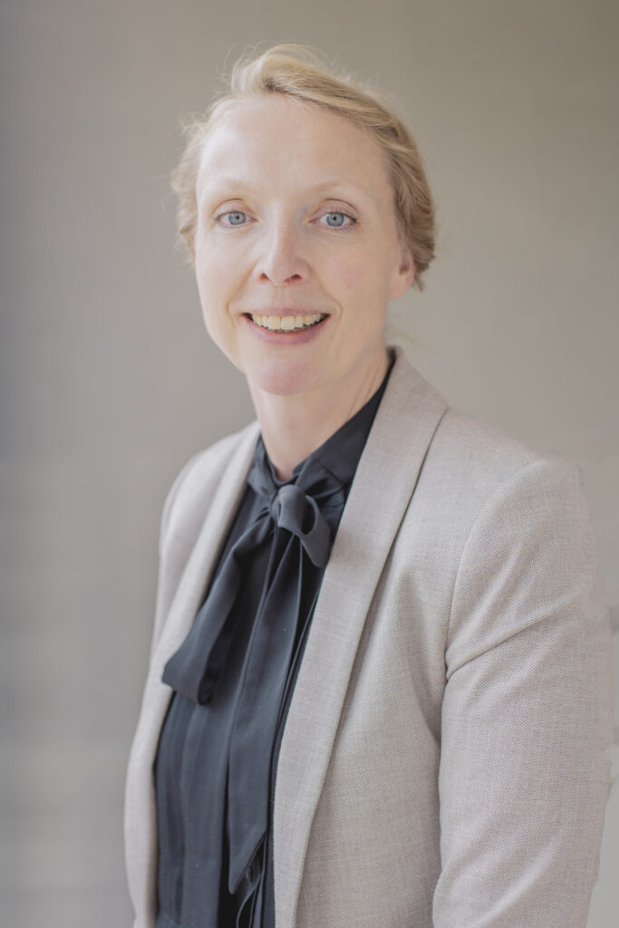 Tamar Hoek, board chair of the SAC, wearing a taupe blazer and black tie-neck blouse. Hoek detailed milestones.