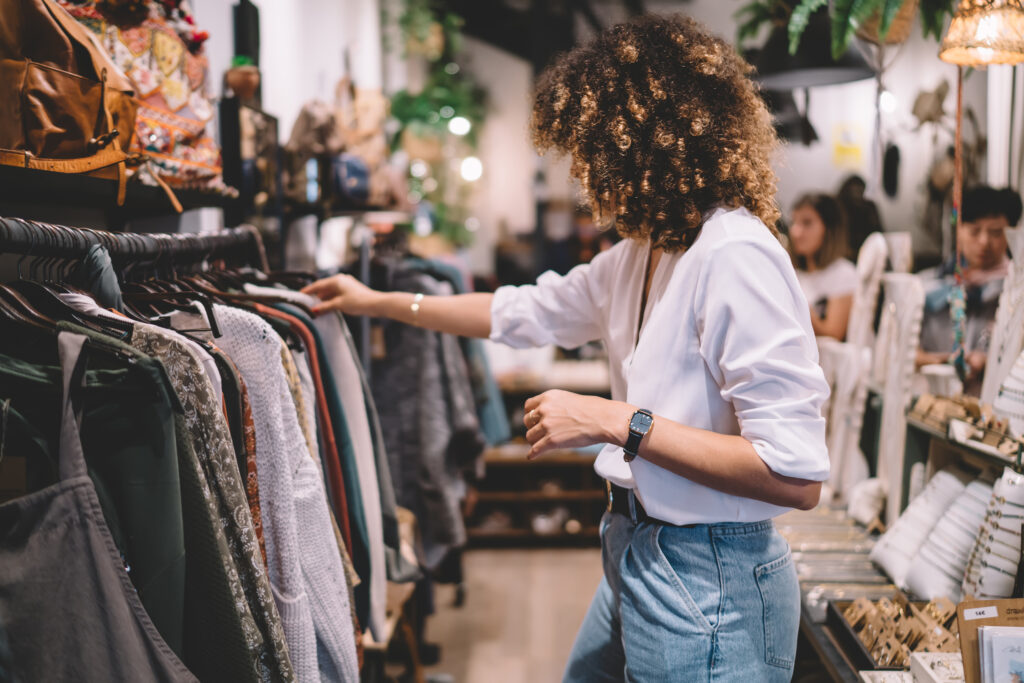 Caucaisan female customer with curly hair buying clothes in boutique