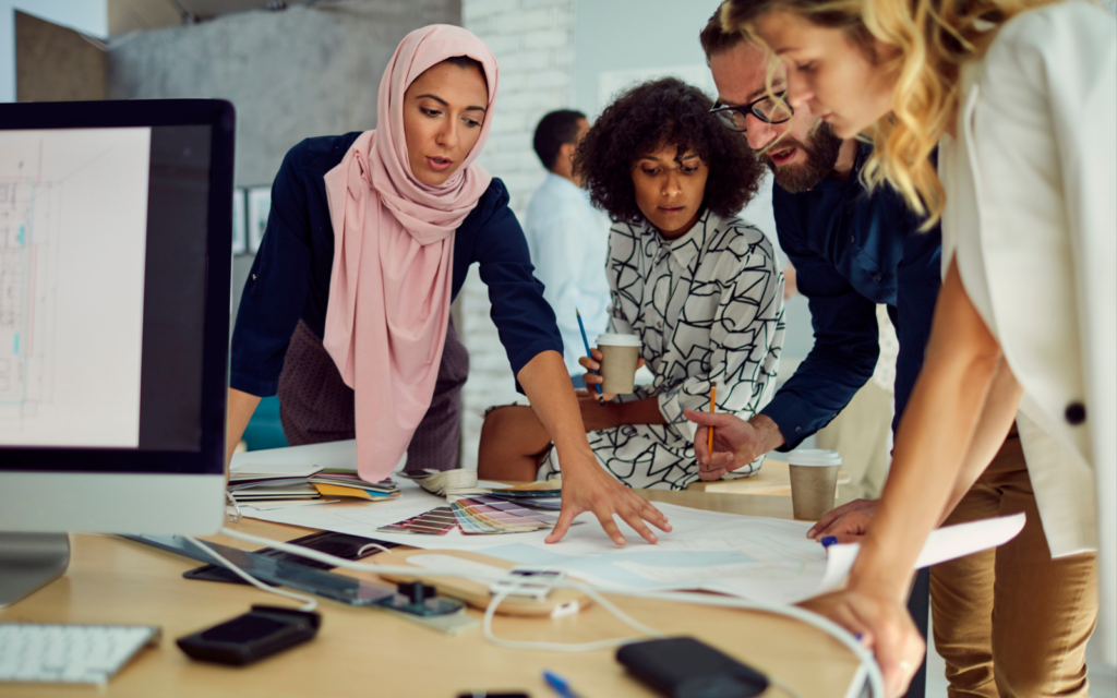 Photo of a group of people stood around a table working collaboratively