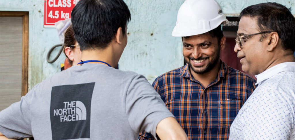 View of smiling contractors, one with back facing the camera whose shirt says The North Face.